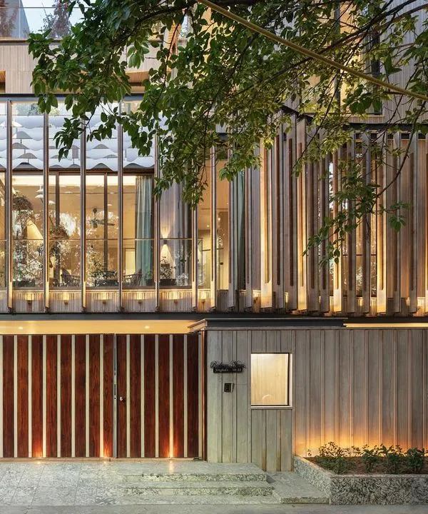 This residence in Punjabi Bagh, Delhi, showcases our approach to modern luxury. The design uses glass boxes and pergola-like screens to create a porous facade, blurring the lines between the lush exterior landscape and the interior living spaces, especially when illuminated at night.