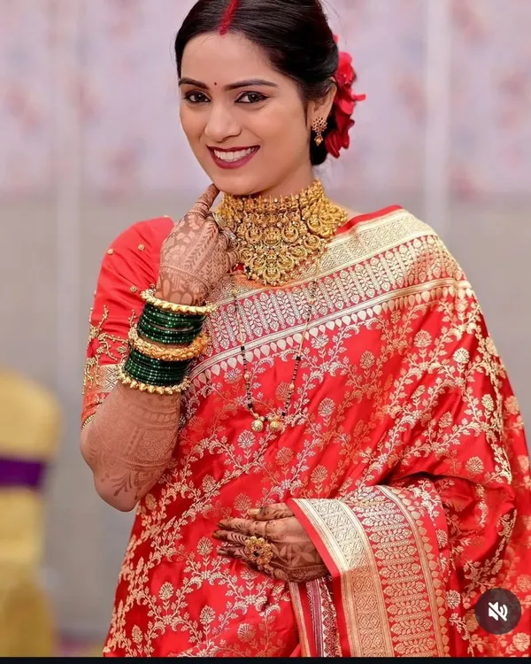 A classic South Indian bridal look featuring a rich red saree and a traditional gold-plated temple jewellery choker.