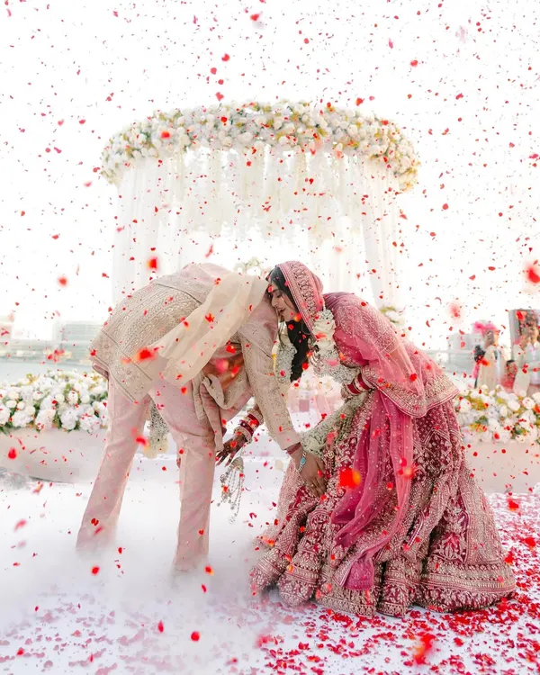 A moment of playful reverence during the varmala ceremony. The shower of petals and clouds of smoke create a magical, dreamlike atmosphere for this key ritual.