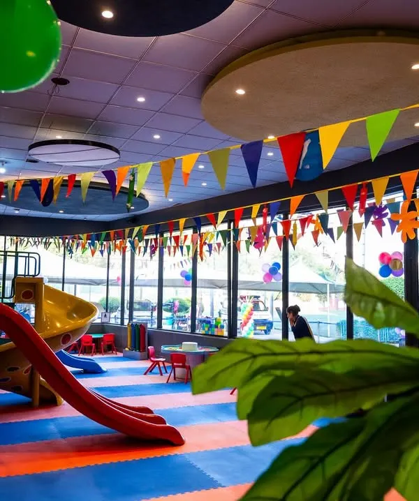 A wide view of the colorful and exciting play area. With slides, climbing structures, and plenty of open space on padded floors, it's a paradise for active kids.