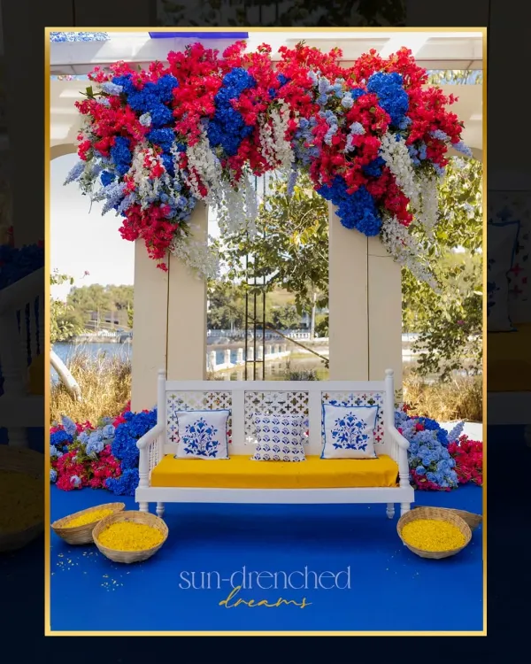 For this Haldi in Udaipur, we created a sun-drenched dream with a Caribbean-inspired theme. The seating for the couple was set against a backdrop of bold red, blue, and white flowers, overlooking the lake.