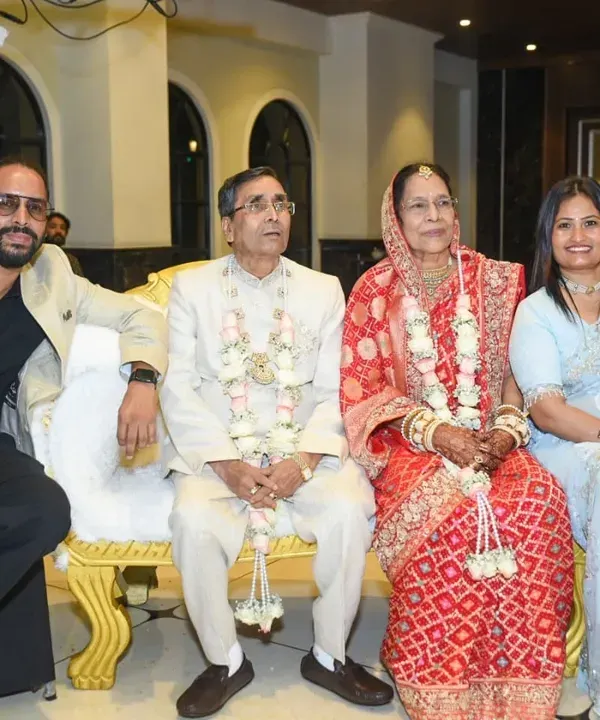 A beautiful family portrait from a 50th wedding anniversary celebration. The happy couple is seated on a grand sofa, surrounded by their children.