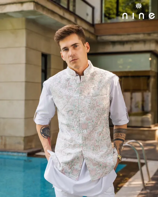 This sleeveless vest, with its delicate pastel floral embroidery, is a perfect example of effortless style. Paired with a simple white kurta, it's an ideal outfit for a daytime festive event or a Haldi ceremony.