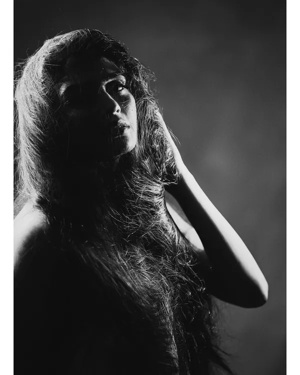 A dramatic black and white portrait where the hair becomes a key visual element. The strong side lighting carves out the subject's features and creates a powerful, artistic mood.