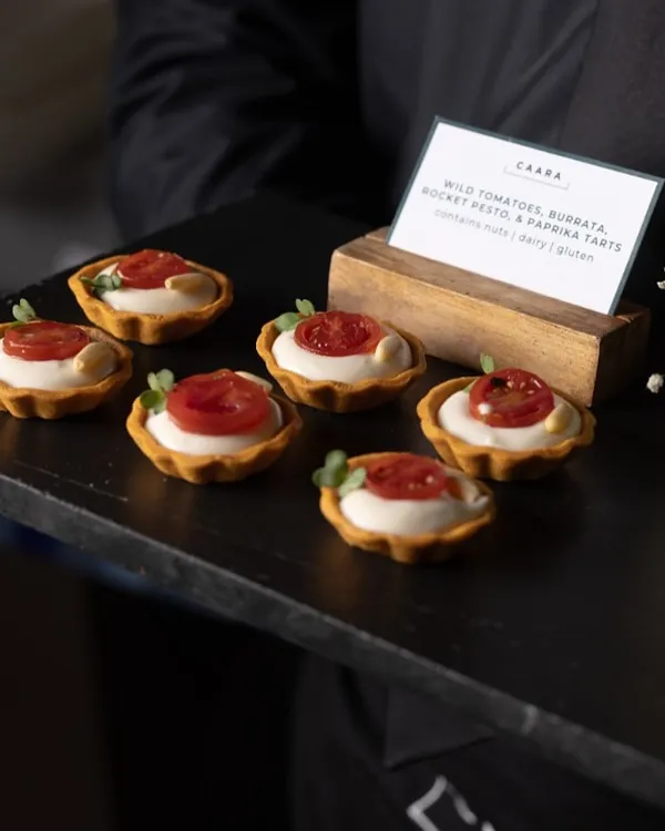 Wild tomato, burrata, and pesto tartlets, a perfect bite-sized appetizer. These gluten-free tarts are a crowd favorite, combining the freshness of cherry tomatoes with creamy burrata and our farm-fresh basil pesto.