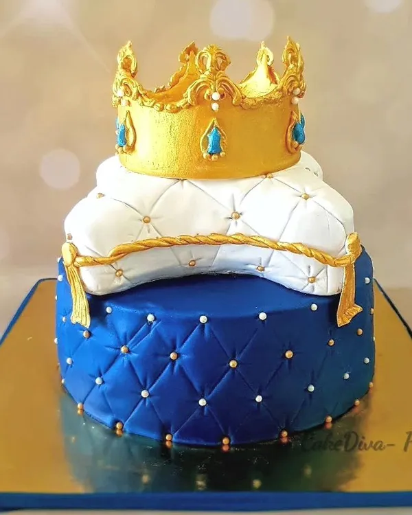 A royal birthday cake for a little prince's first birthday. This two-tier cake features a royal blue quilted fondant base and a white pillow tier, topped with a hand-sculpted golden fondant crown. The flavor inside was a rich chocolate hazelnut.
