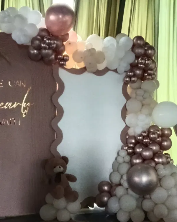 A close-up of my "We Can Bearly Wait" teddy bear theme. This shows the custom scalloped backdrop and a detailed organic balloon arch in rose gold, beige, and white, with a small teddy bear prop nestled in the balloons.
