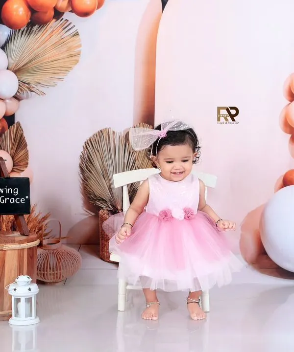 A beautiful portrait of a young girl in a pink dress, sitting in a boho-chic setup. The sign "Growing With Grace" perfectly captures this stage of her childhood.