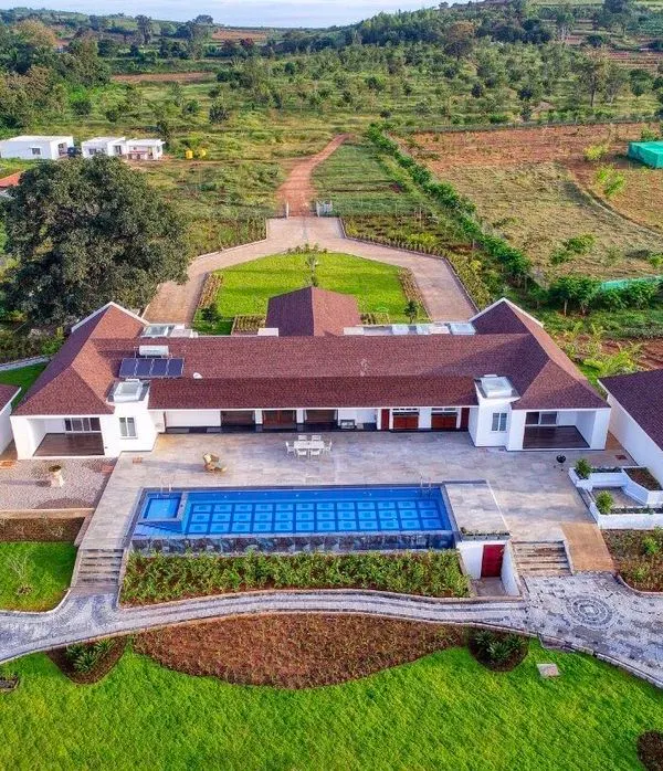 This aerial perspective of a farmhouse estate on the backwaters of Kabini captures the essence of our large-scale design capabilities. We sculpted the land to include expansive lawns, a formal driveway, and an infinity pool that seamlessly blends with the home and the vast landscape beyond.