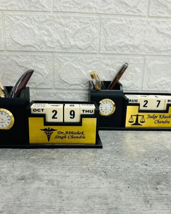This image shows two of my lifetime calendar desk organizers side-by-side. They feature a perpetual block calendar, an analog clock, and pen holders, customized here for a doctor and a judge with their names and professional symbols.