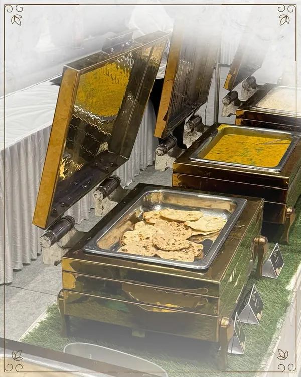 Our buffet setups are a feast for the eyes, featuring elegant brass and copper chafing dishes. Here, we showcase a spread of classic Indian main courses, including dal and fresh rotis.