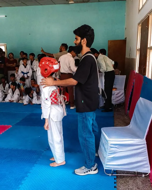 As a coach, I ensure my students are properly protected before they begin sparring, adjusting a student's headgear.