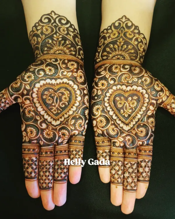 A modern take on bridal mehndi with a bold, symmetrical heart at the center of the palms, surrounded by intricate swirls and patterns.