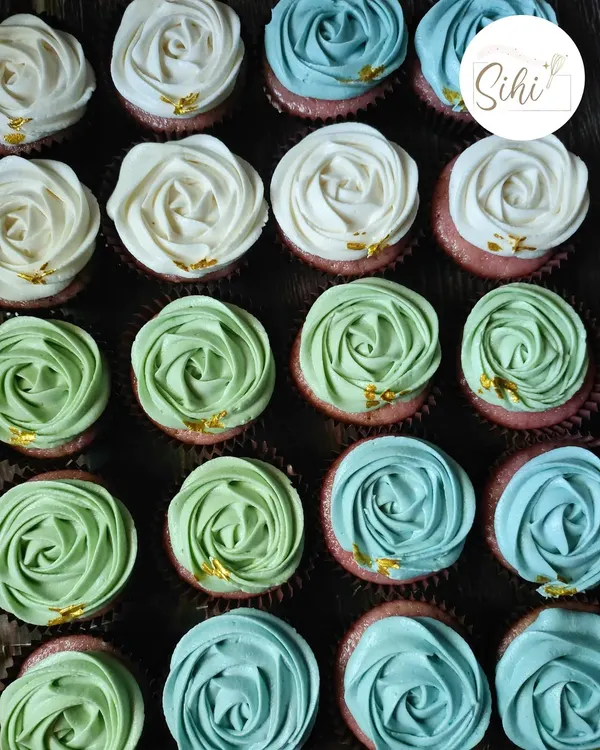 I love this color combination. These are my signature rosette cupcakes in shades of white, sage green, and sky blue, each dotted with a tiny flake of edible gold leaf.