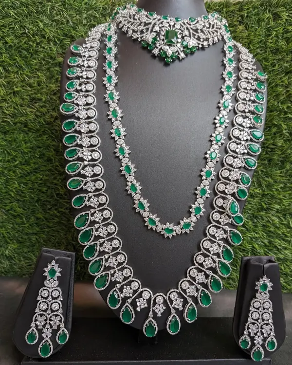This is the ultimate reception look! A grand two-layered American Diamond haaram with emerald stones, paired with a matching choker and earrings. This set is designed to make you feel like a star on your big day.