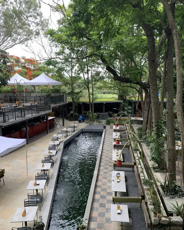 This is the view of our brewery's outdoor seating area. The tables are set alongside a serene water channel, surrounded by trees, offering a dining experience that feels miles away from the city.