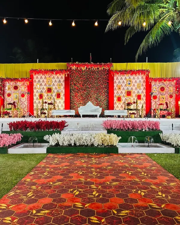 This grand reception stage is a celebration of traditional Indian design. I used panels with classic motifs, a backdrop of red roses, and elegant white seating to create a royal and opulent look.