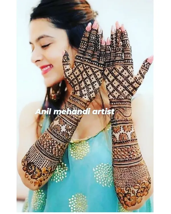 A happy client showing off her full-hand mehandi. The design features a classic criss-cross net pattern that looks stunning with the dark henna stain.