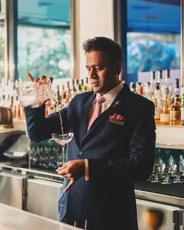A bartender at Yauatcha expertly pouring a cocktail. This action portrait captures a moment of focus and skill, highlighting the craftsmanship that goes into every drink and adding a human touch to the bar experience.