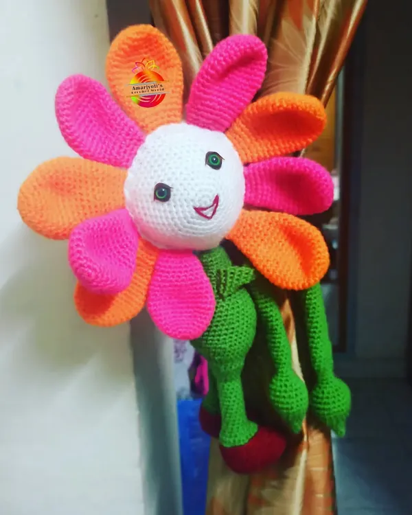 This large, colorful flower doll curtain holder is designed to bring a smile to your face. Its long arms wrap around the curtain, adding a bright and cheerful touch to the room's decor.