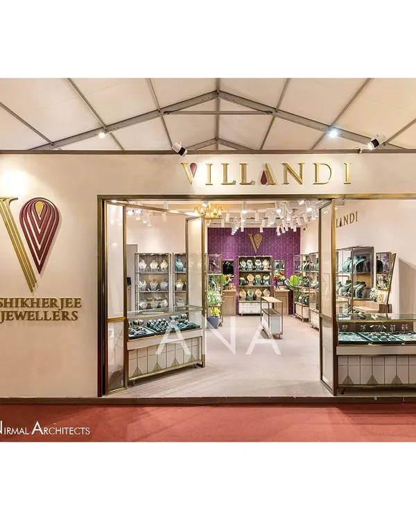 The main entrance to the Villandi Jewellers stall at Bridal Asia '23. The design features a clean, off-white facade with elegant brass-framed glass, creating a luxurious and inviting storefront that allows glimpses of the collection inside.