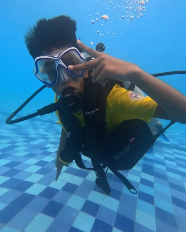 A young participant gives a cool sign underwater during his first scuba experience in a pool. Our introductory courses are all about building confidence safely.