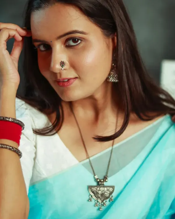 A beautiful close-up portrait of a model in a light blue saree, looking directly at the camera with a confident and engaging expression.
