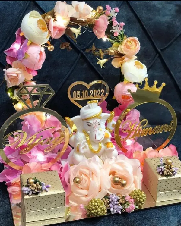 An elaborate engagement ring platter featuring a Ganesha idol, personalized name cutouts, and beautiful floral decorations with fairy lights.