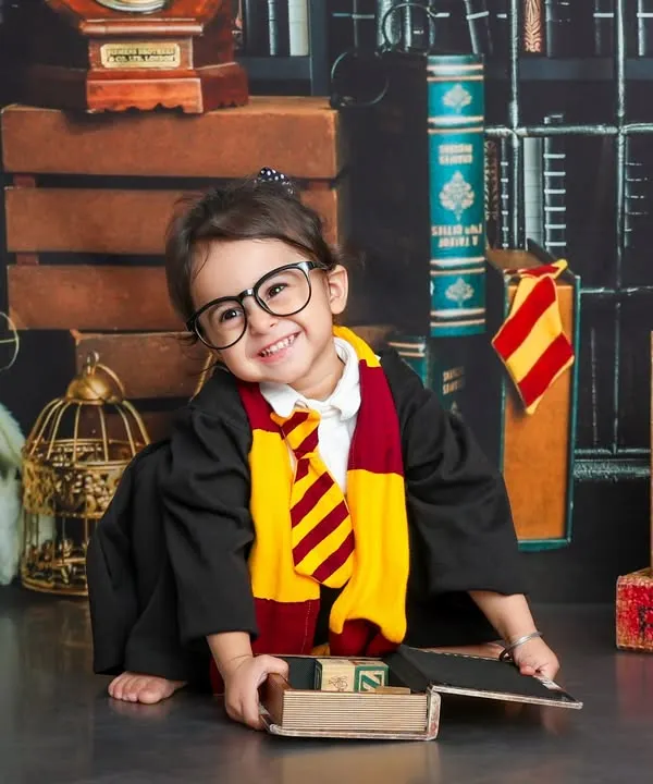 Welcome to Hogwarts. This little wizard, with her round glasses and Gryffindor scarf, is ready to cast a spell of cuteness in our magical library set.