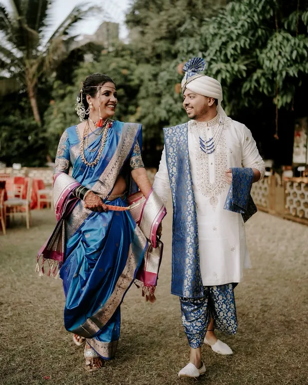 A beautiful moment between the bride and groom, captured outdoors. The bride looks radiant in her royal blue Paithani saree, a classic choice for Maharashtrian weddings, showcasing the rich textile heritage.