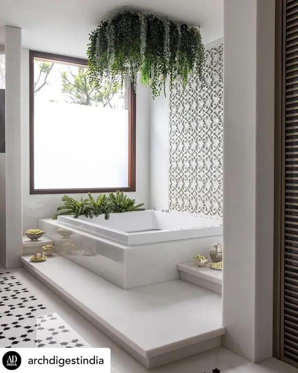 This is a home spa we designed to be a bright, airy sanctuary. The jacuzzi is surrounded by white marble and lush greenery, with a hanging plant installation that adds a touch of drama. The intricate mother-of-pearl jaali on the wall is a beautiful example of detailed craftsmanship.