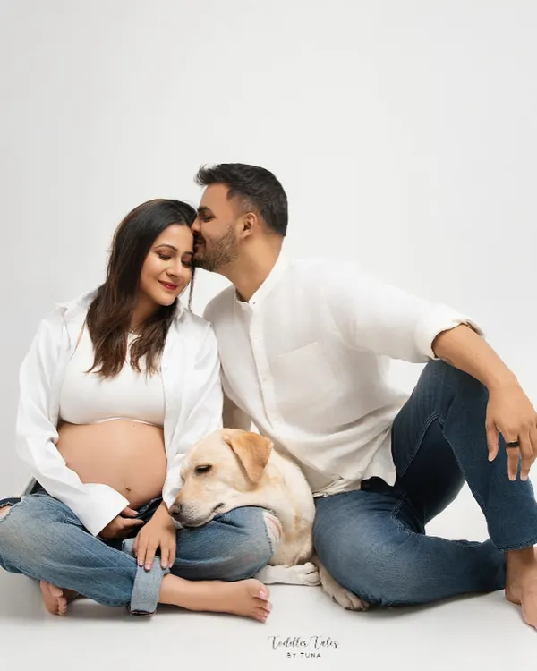 A family portrait in the making. This tender moment, with the partner's kiss and the loyal dog resting his head, perfectly captures the love that fills this growing family's home.