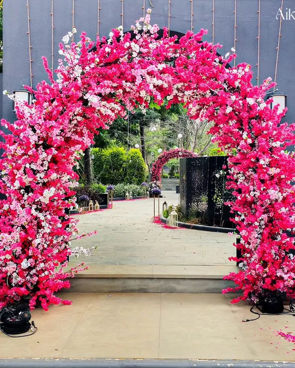 A breathtaking cherry blossom-style floral arch in vibrant shades of pink. This entrance creates an immersive, fairytale-like experience for guests as they walk into the event.