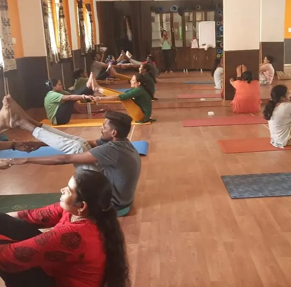 The studio filled with energy during a partner yoga class. Here, students are practicing Navasana (Boat Pose) together, using each other for support and balance. It’s a playful way to build core strength and trust.