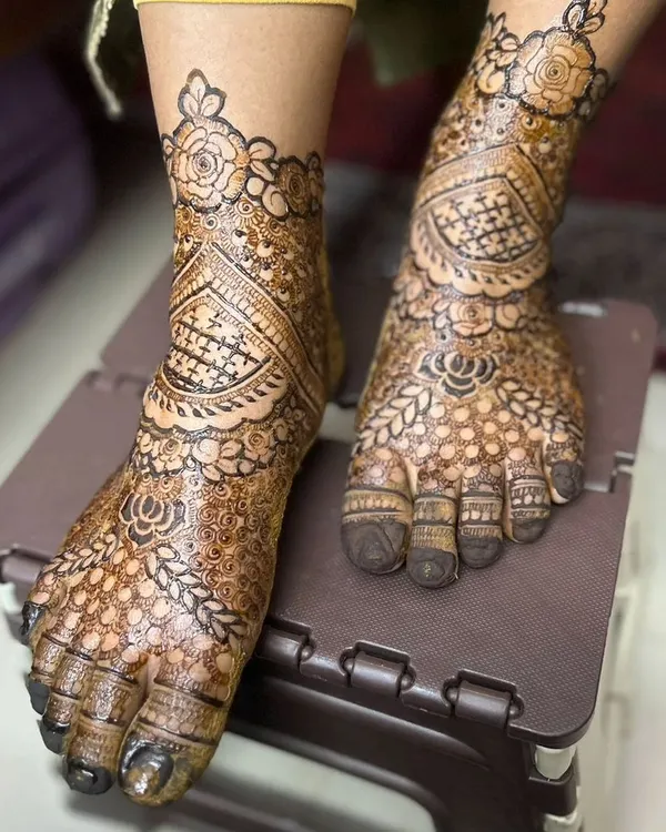 A close-up of a bridal feet design. The pattern is dense and intricate, with a beautiful floral band around the ankle, perfectly framing the foot.