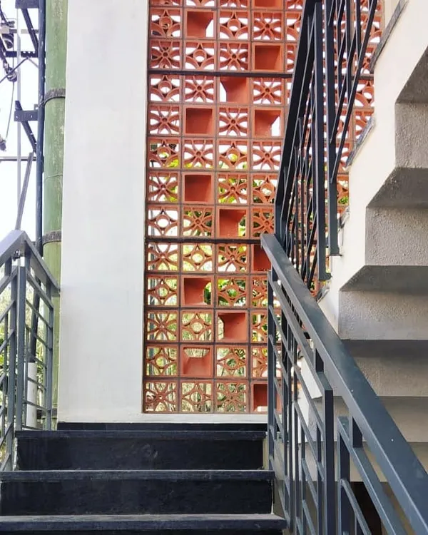 A terracotta jaali screen provides a beautiful, porous barrier for a staircase. It allows for ventilation and the passage of dappled light while adding a rich, earthy texture to the space.