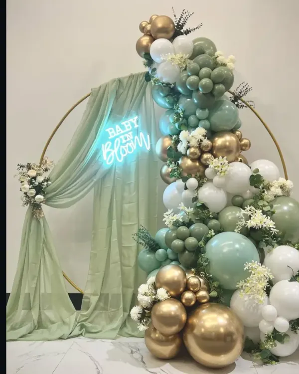 A beautiful 'Baby in Bloom' backdrop I designed for a baby shower. The sage green, white, and gold balloon arch with a custom neon sign is a popular and elegant choice.
