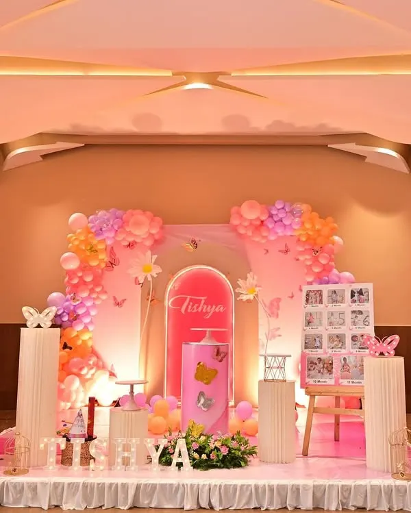 A wide view of a butterfly-themed stage, featuring large cutout wings and soft pink lighting. This setup is perfect for a grand hall and creates a beautiful photo opportunity.