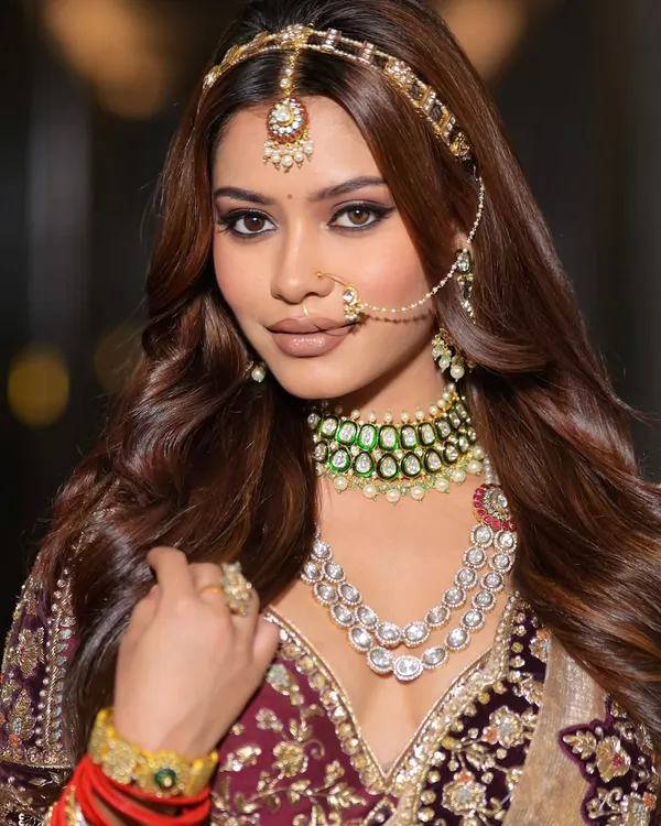 This is the essence of a modern maharani look. A close-up showcasing the sharp, defined winged eyeliner and soft, blended eyeshadow that create a captivating gaze. The makeup is designed to complement the heavy bridal jewelry and rich maroon outfit, creating a look that is both traditional and stunningly contemporary.