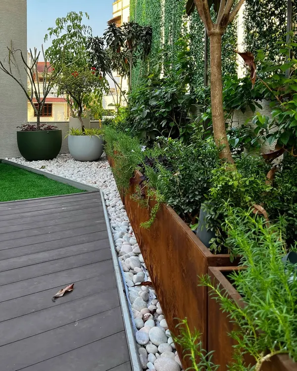 At the 'House of Terraces,' I used Corten steel planters to create a warm, tactile boundary between the deck and the greenery. A pebble-filled drainage channel is both a functional solution and a beautiful design detail.