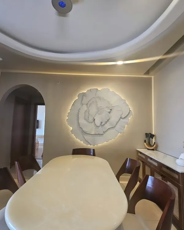 The 3D floral art installed in a client's dining room, where the backlighting creates a soft, ambient glow. It serves as a serene and elegant focal point, complementing the modern interior.