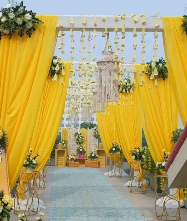 An inviting entrance I created for a Haldi ceremony, with bright yellow drapes and hanging floral tassels. The custom welcome sign for Gaurav and Sanchikha adds a personal touch right from the start.