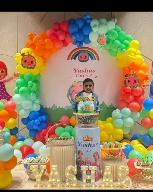 A vibrant Cocomelon themed birthday party for a 3-year-old. This colorful setup features a rainbow balloon arch, character cutouts of JJ and friends, and a personalized backdrop.