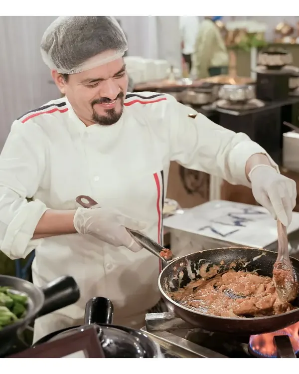 Our chef expertly preparing a dish at a live cooking station. This service adds a dynamic element to your event, as guests watch their food being cooked to perfection right before their eyes.