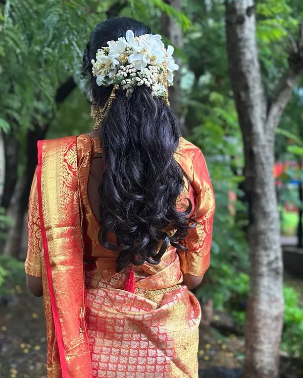 A beautiful half-up, half-down hairstyle with soft curls, adorned with fresh white flowers. This is a classic choice for South Indian brides and looks incredibly romantic.