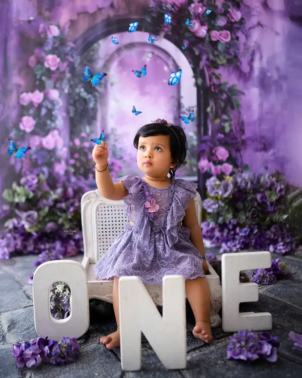 A magical first birthday in an enchanted purple forest. This little one is captivated by the fluttering butterflies in this dreamy, creative setup.