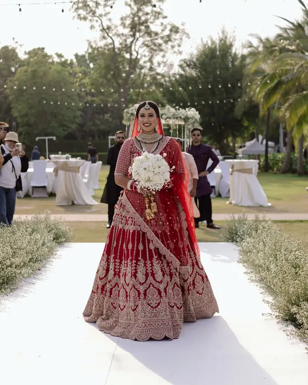 She wore hope, grace, and a promise that forever is hers. A classic bridal entry shot, capturing the bride in her magnificent red lehenga as she walks down the aisle at her Thailand wedding.