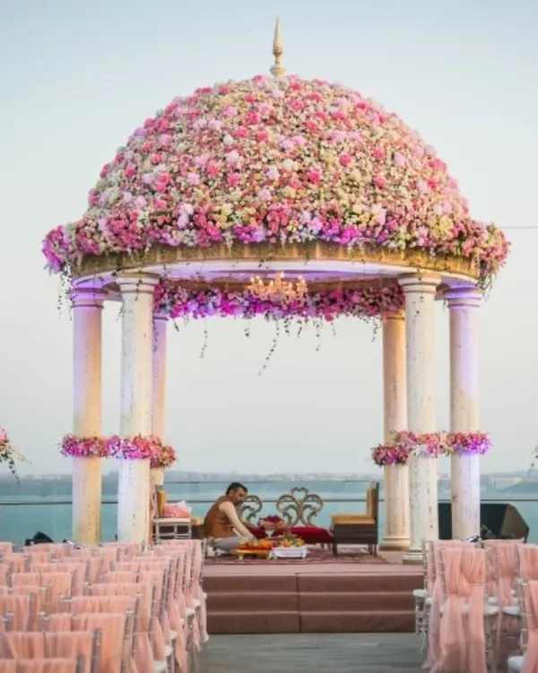 A breathtaking mandap with a dome made entirely of pink and peach roses, set against the serene water. This is the epitome of a fairytale wedding, where my team and I turn romantic dreams into reality.
