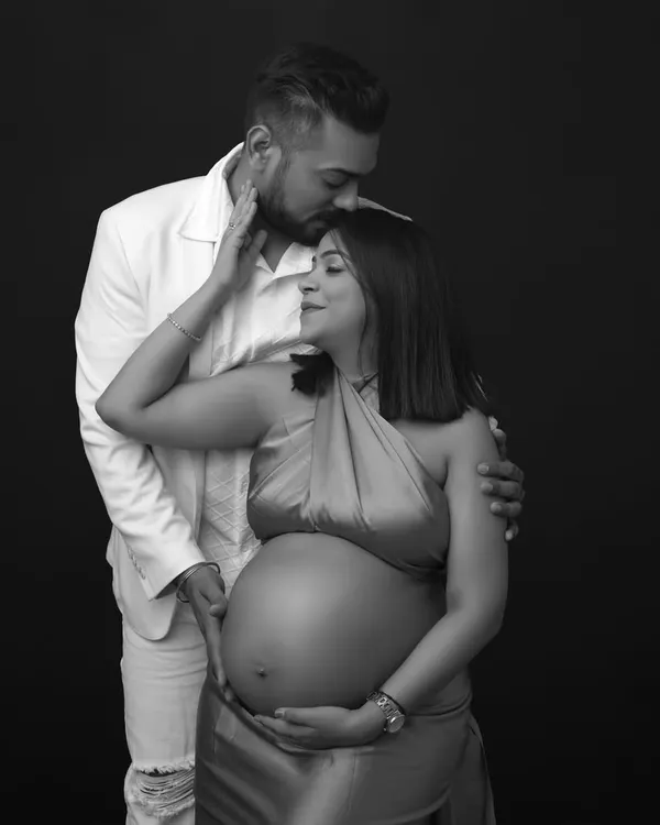 Pure love in every frame. This black and white portrait captures a tender moment, with the dad-to-be placing a gentle kiss on his partner's forehead.