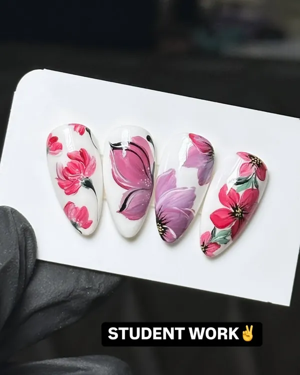 This is the level of detail and artistry my students achieve. This example of student work shows intricate, hand-painted floral designs on almond-shaped nail tips, demonstrating the high-quality techniques taught in my nail art design workshops.